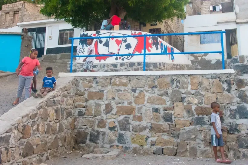 A group of children are playing in front of a building with the word freedom painted on it