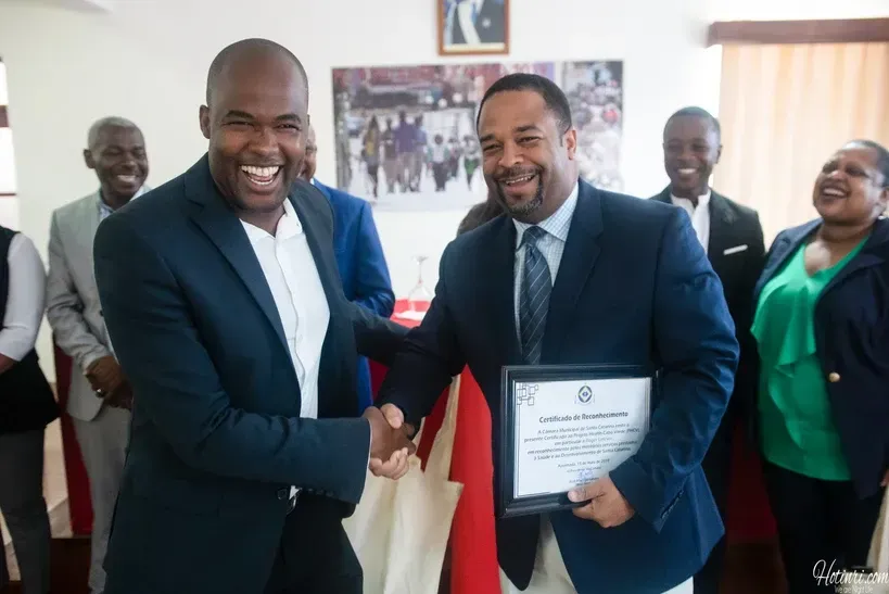 A man in a suit and tie is shaking hands with another man while holding a certificate.