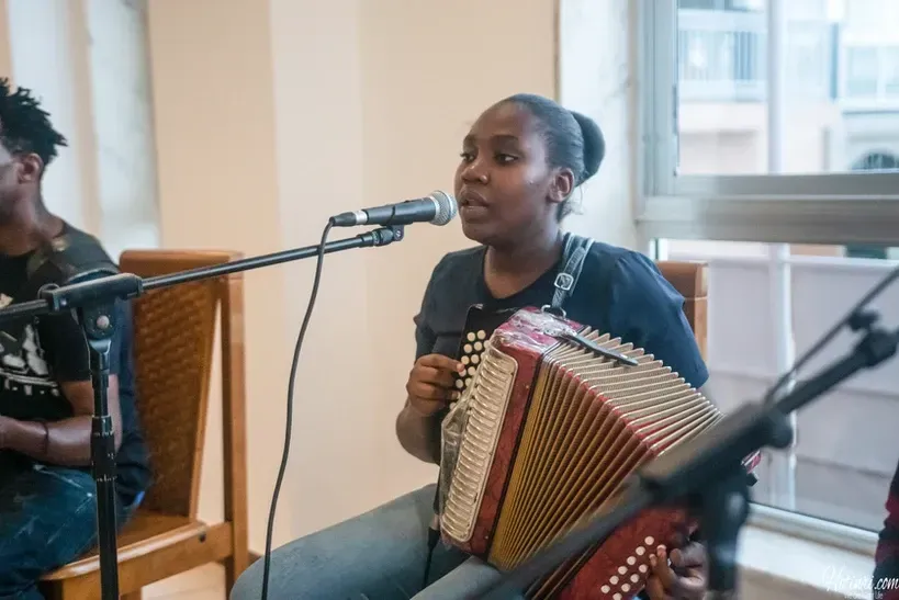 A woman is playing an accordion and singing into a microphone.