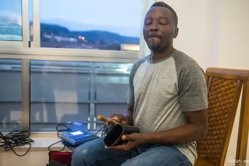A man is sitting in a chair playing a drum.