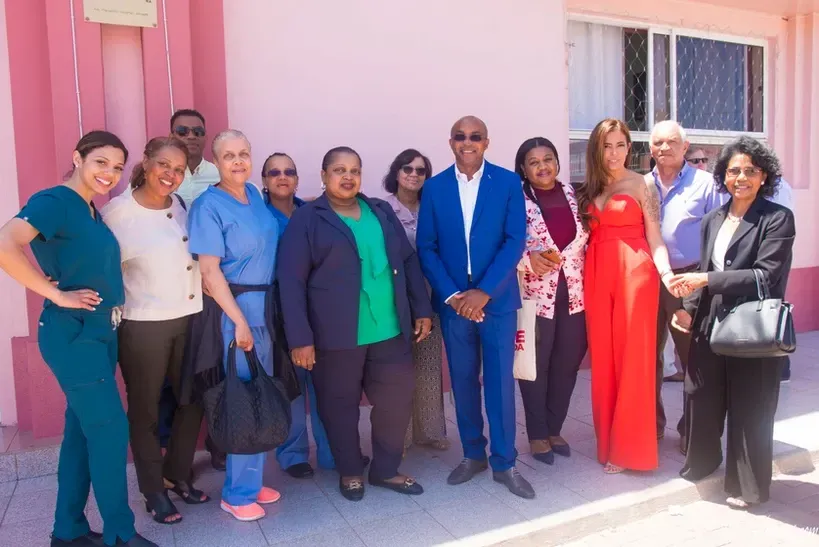 A group of people are posing for a picture in front of a pink building.