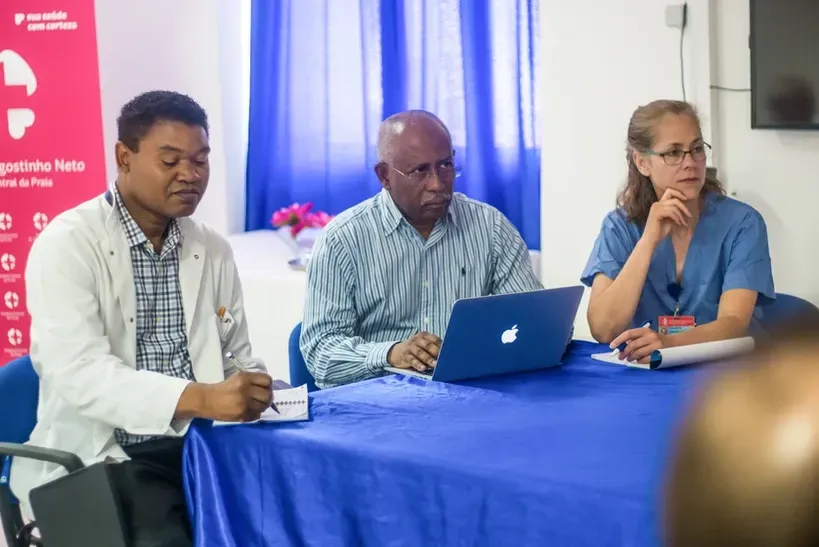 A group of people are sitting at a table with a laptop.