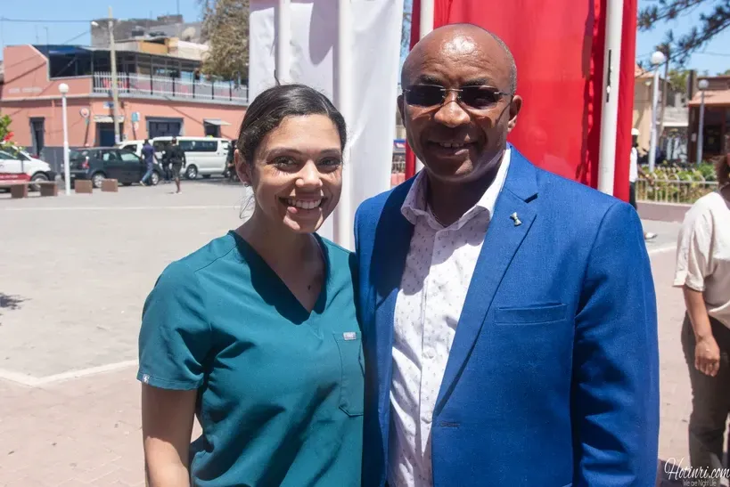 A man in a blue suit and a woman in scrubs are posing for a picture.