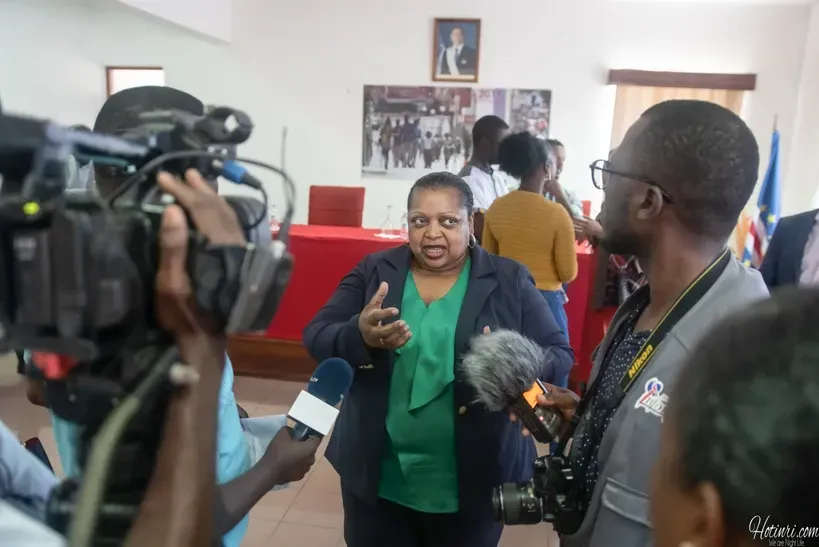 A woman is being interviewed by a group of people while a man holds a camera.