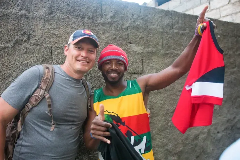 A man in a gray shirt is standing next to a man in a colorful tank top