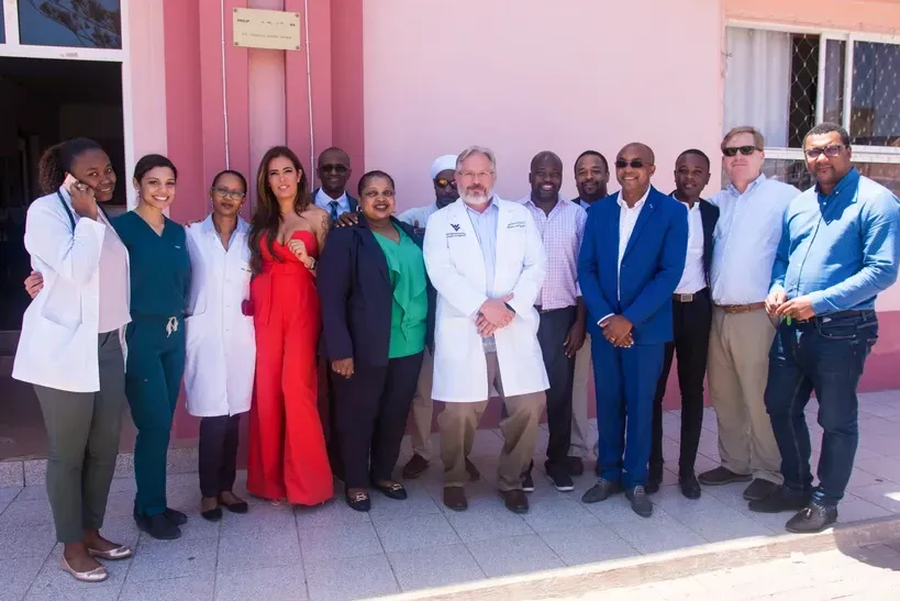 A group of people are posing for a picture in front of a pink building.