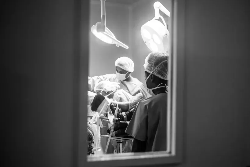 A group of surgeons are operating on a patient in an operating room.