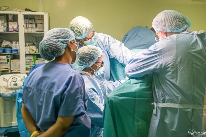 A group of surgeons are operating on a patient in an operating room.