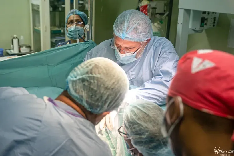 A group of surgeons are operating on a patient in an operating room.