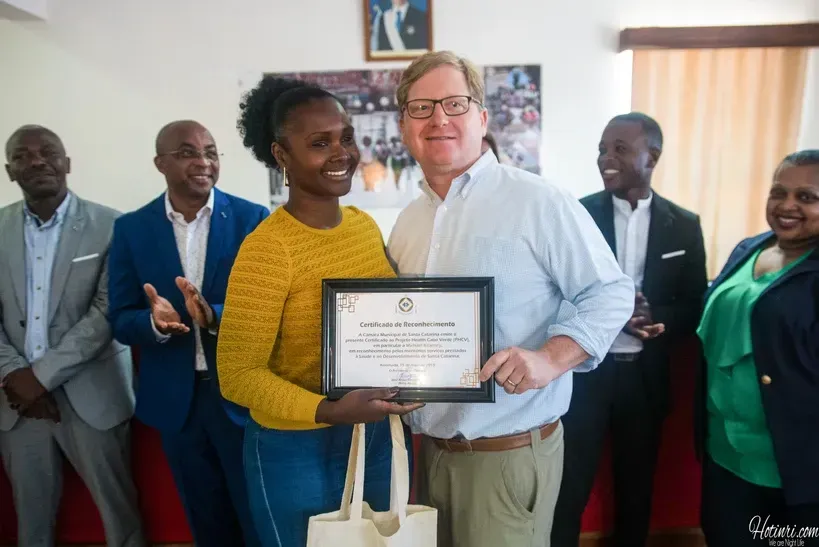 A group of people are standing around a woman holding a certificate.