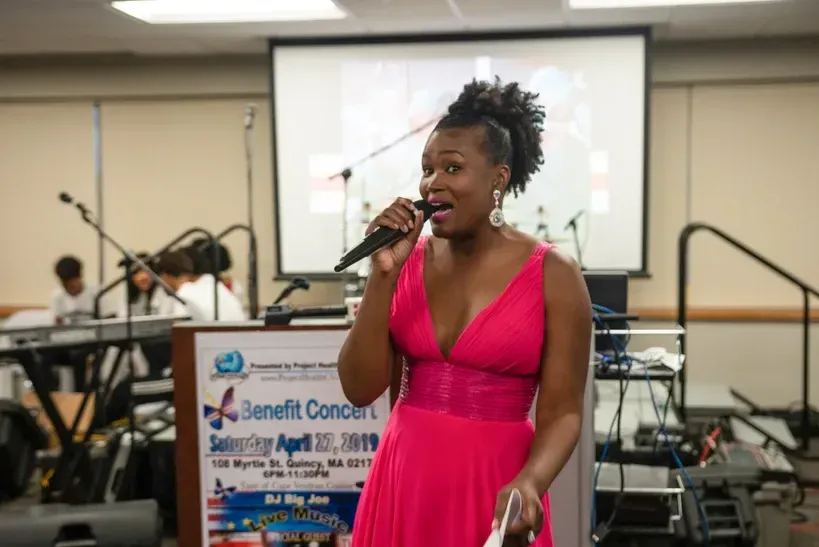 A woman in a pink dress is singing into a microphone.