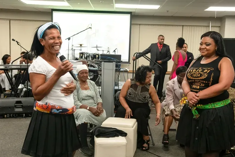 A woman is speaking into a microphone in front of a group of people