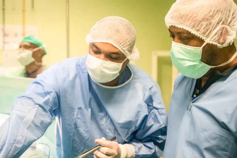 Two surgeons are operating on a patient in an operating room.