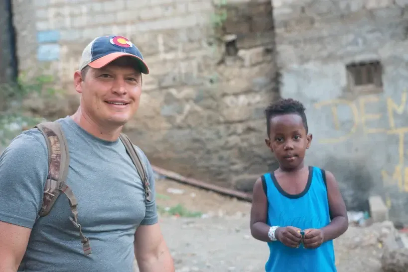 A man and a boy are standing next to each other in front of a building.