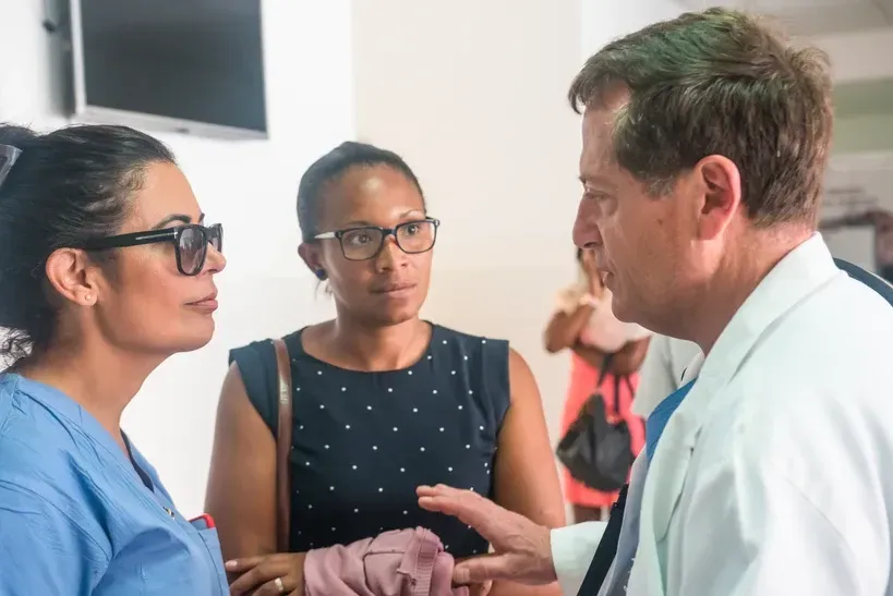 A doctor is talking to two women in a hospital room.