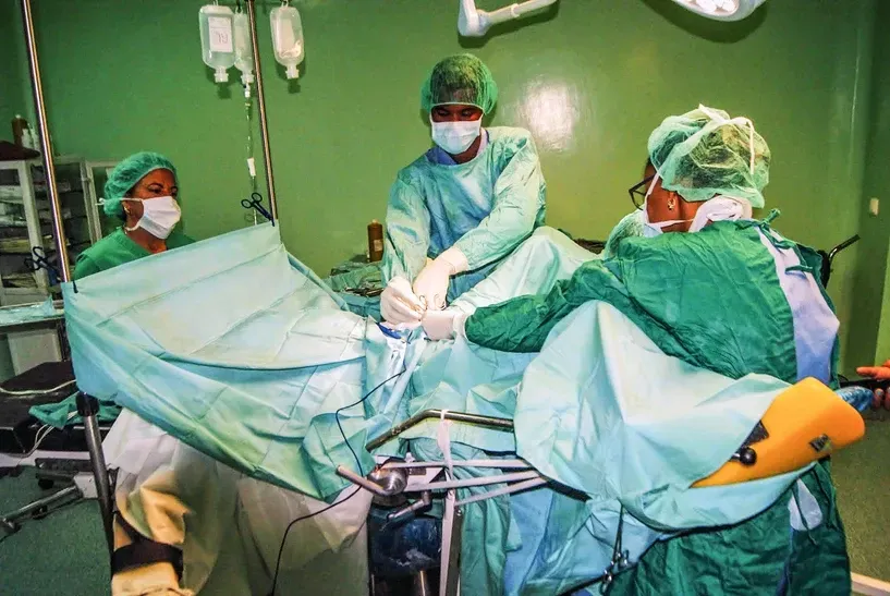 A group of surgeons are operating on a patient in an operating room.