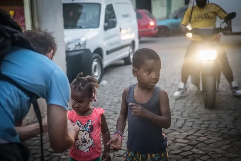 A man is taking a picture of two children on a cobblestone street.