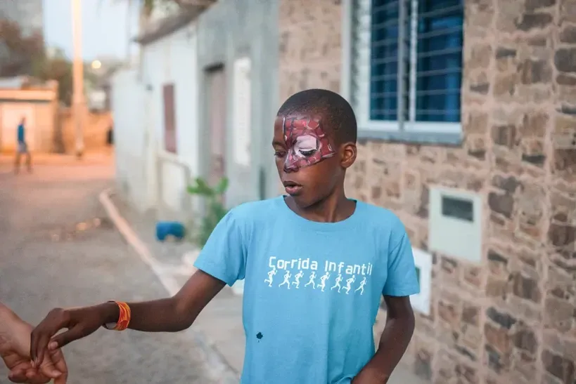 A young boy with a bandage on his face is holding a person 's hand.