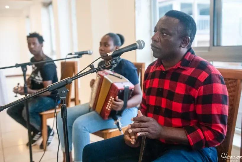 A man in a plaid shirt is playing an accordion in front of a microphone.