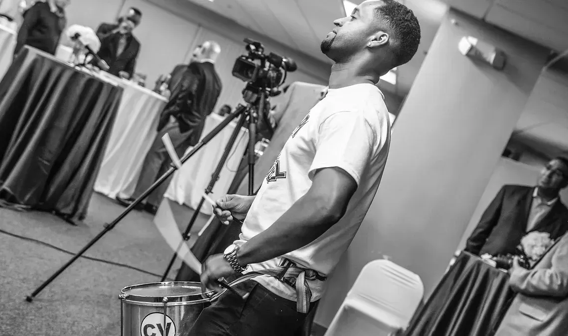 A man is playing a drum in a black and white photo.