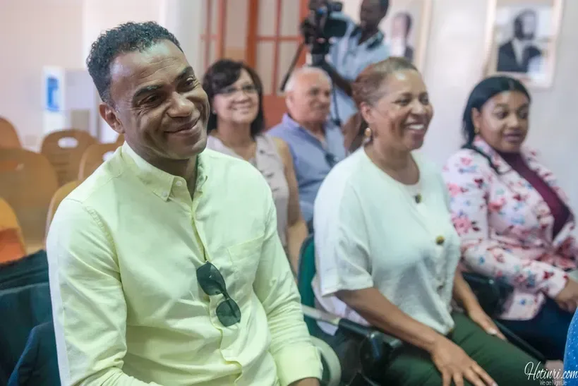 A group of people are sitting in chairs in a room and smiling.