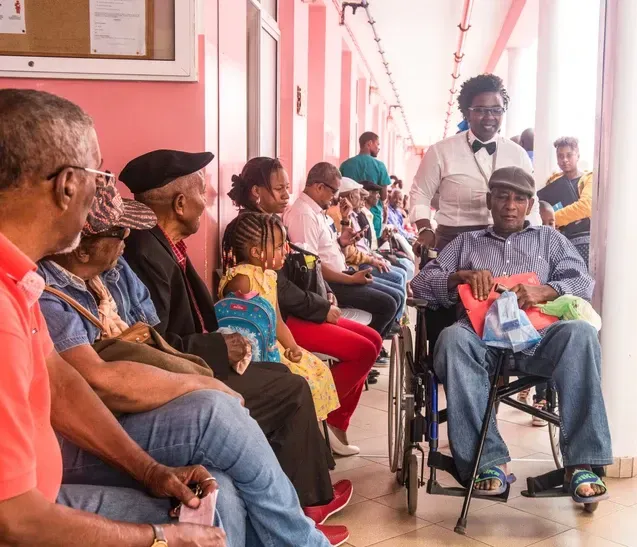 A man in a wheelchair is sitting in a waiting room with other people.