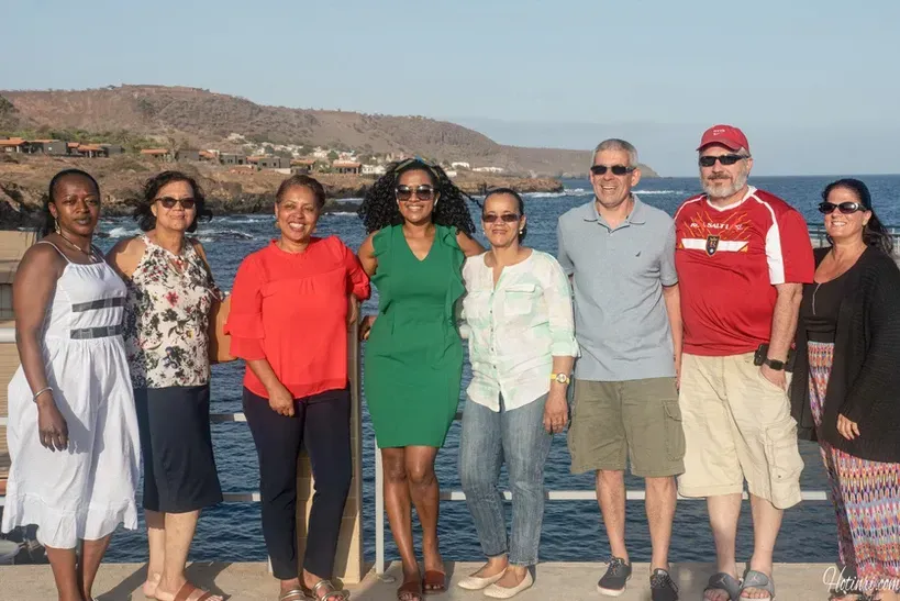 A group of people are posing for a picture in front of the ocean.