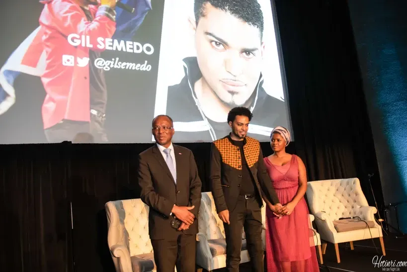 A group of people standing in front of a screen with a picture of a man on it.