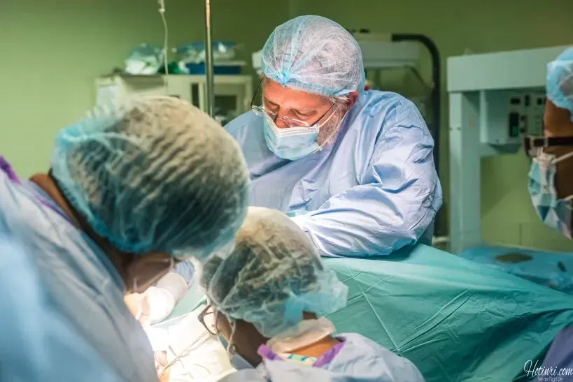 A group of surgeons are operating on a patient in an operating room.