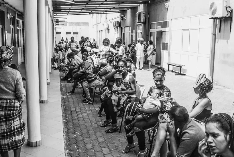A black and white photo of a group of people sitting outside of a building.
