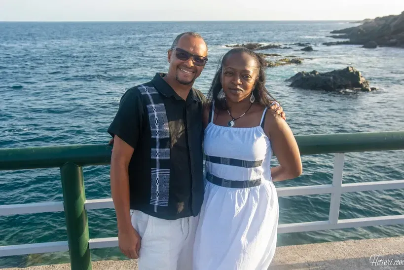 A man and a woman are posing for a picture in front of the ocean
