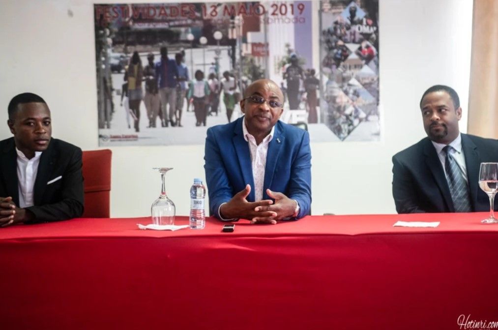 Three men are sitting at a table talking to each other.