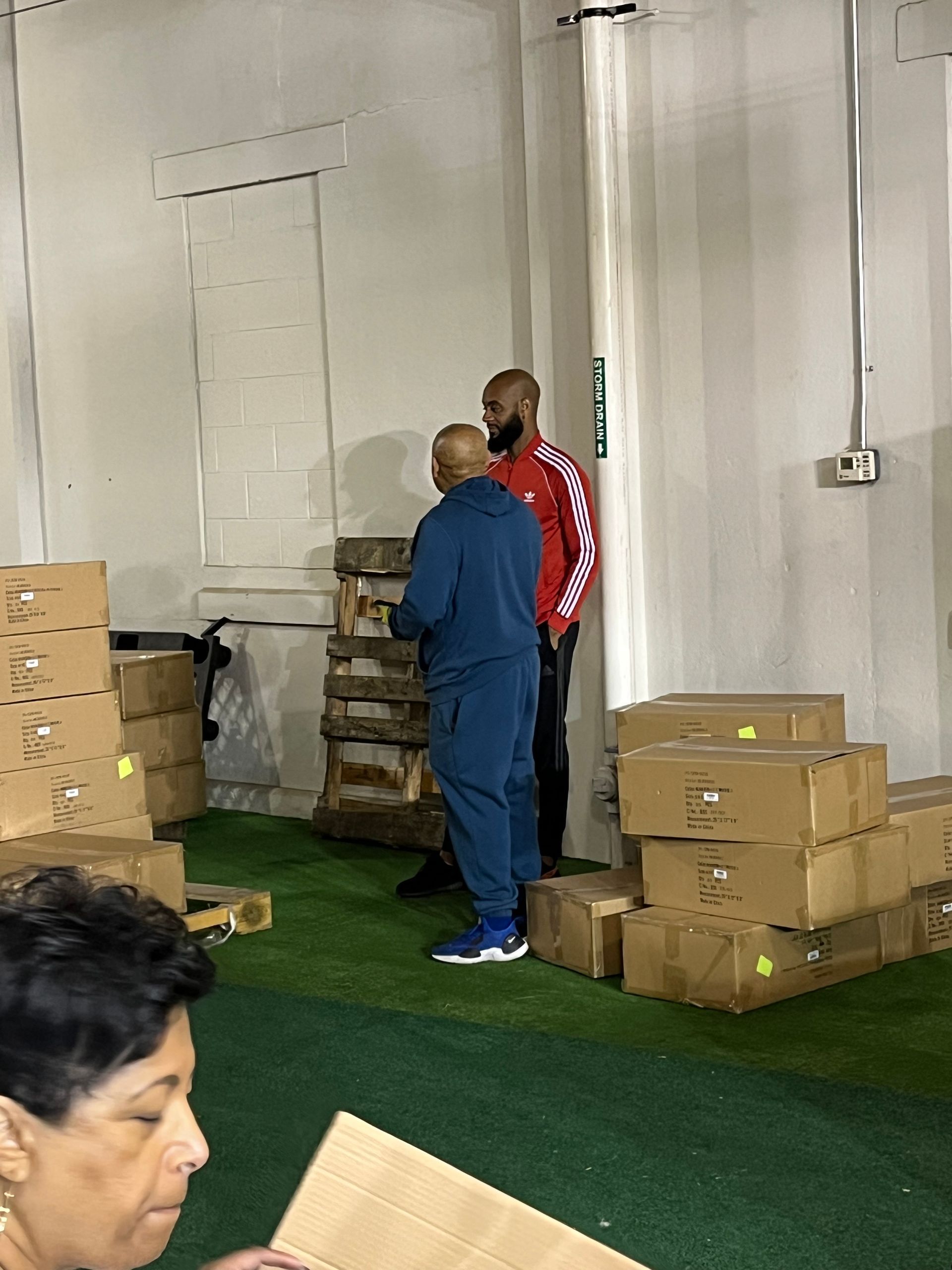 A woman is looking at a cardboard box in a warehouse.