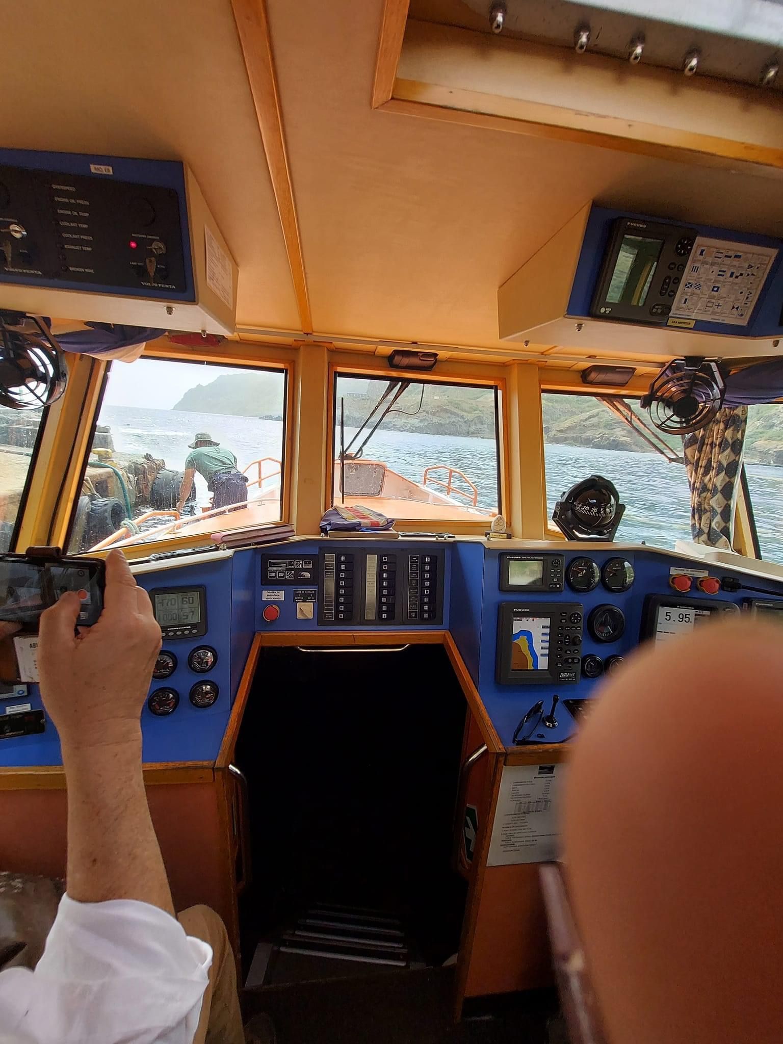 A man is taking a picture of the cockpit of a boat