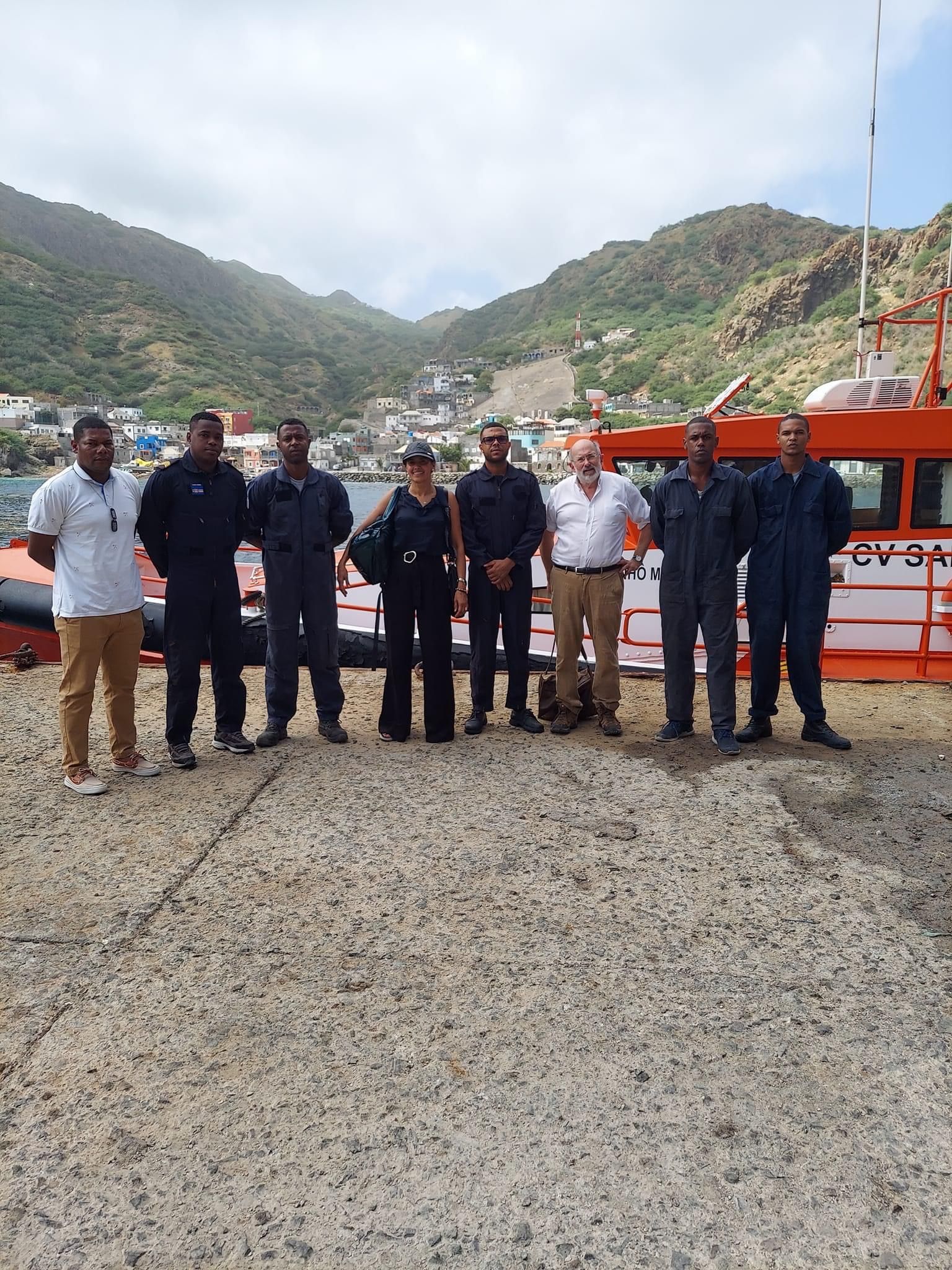 A group of people are posing for a picture in front of a boat.