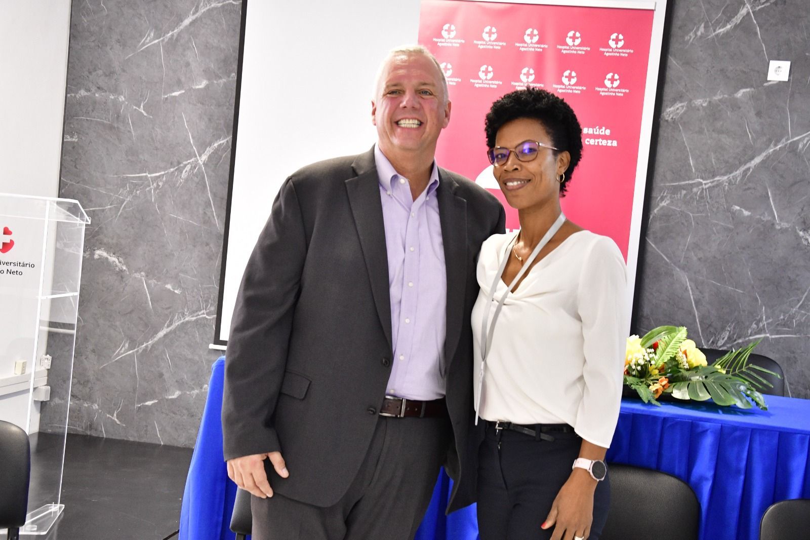 A man in a suit and a woman in a white shirt are posing for a picture.