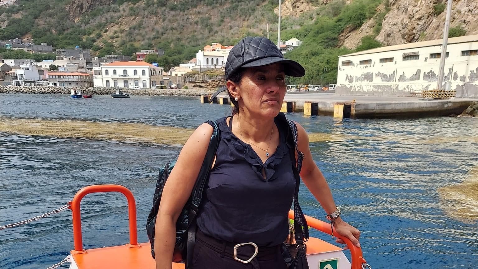 A woman is standing on the back of a boat in the water.