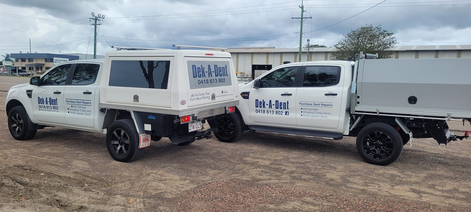Two White Trucks Are Parked Next to Each Other in a Dirt Field — Dek-A-Dent Townsville In Wulguru, QLD