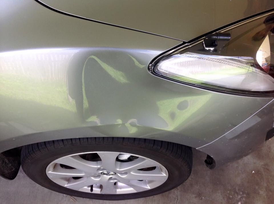 A Silver Car With a Damaged Bumper is Parked in a Garage — Dek-A-Dent Townsville In Wulguru, QLD
