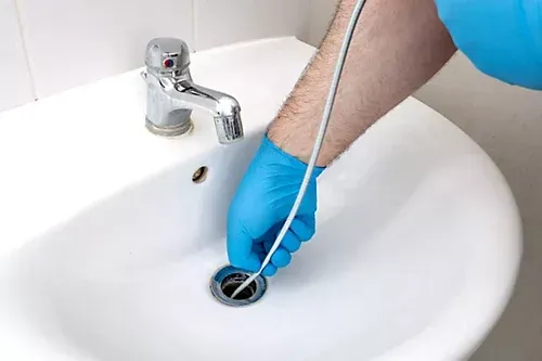A person is cleaning a sink with a hose.