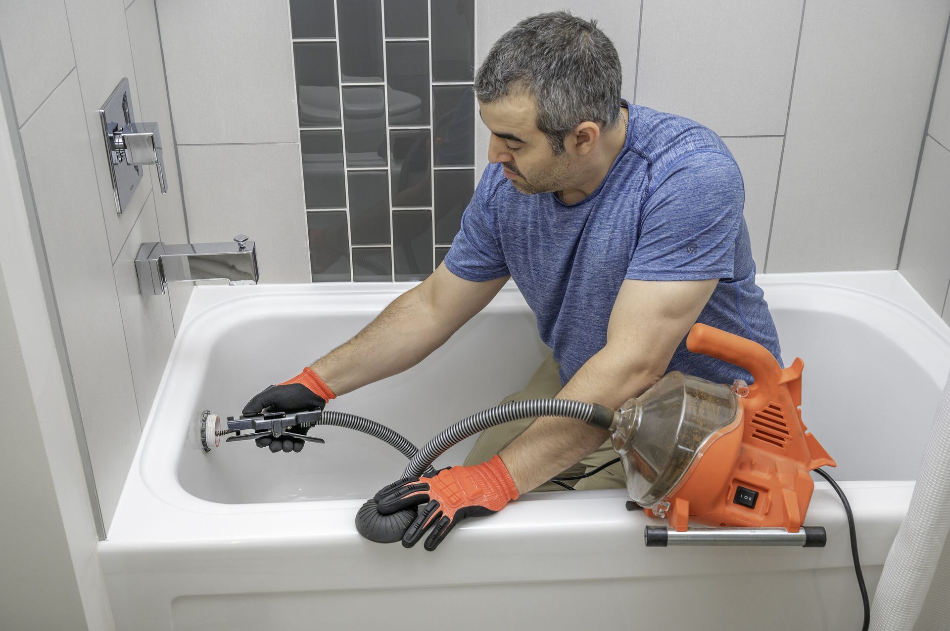 A man is cleaning a bathtub with a drain cleaner.