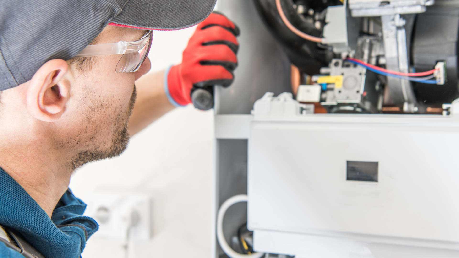 A man is working on a boiler with a screwdriver.