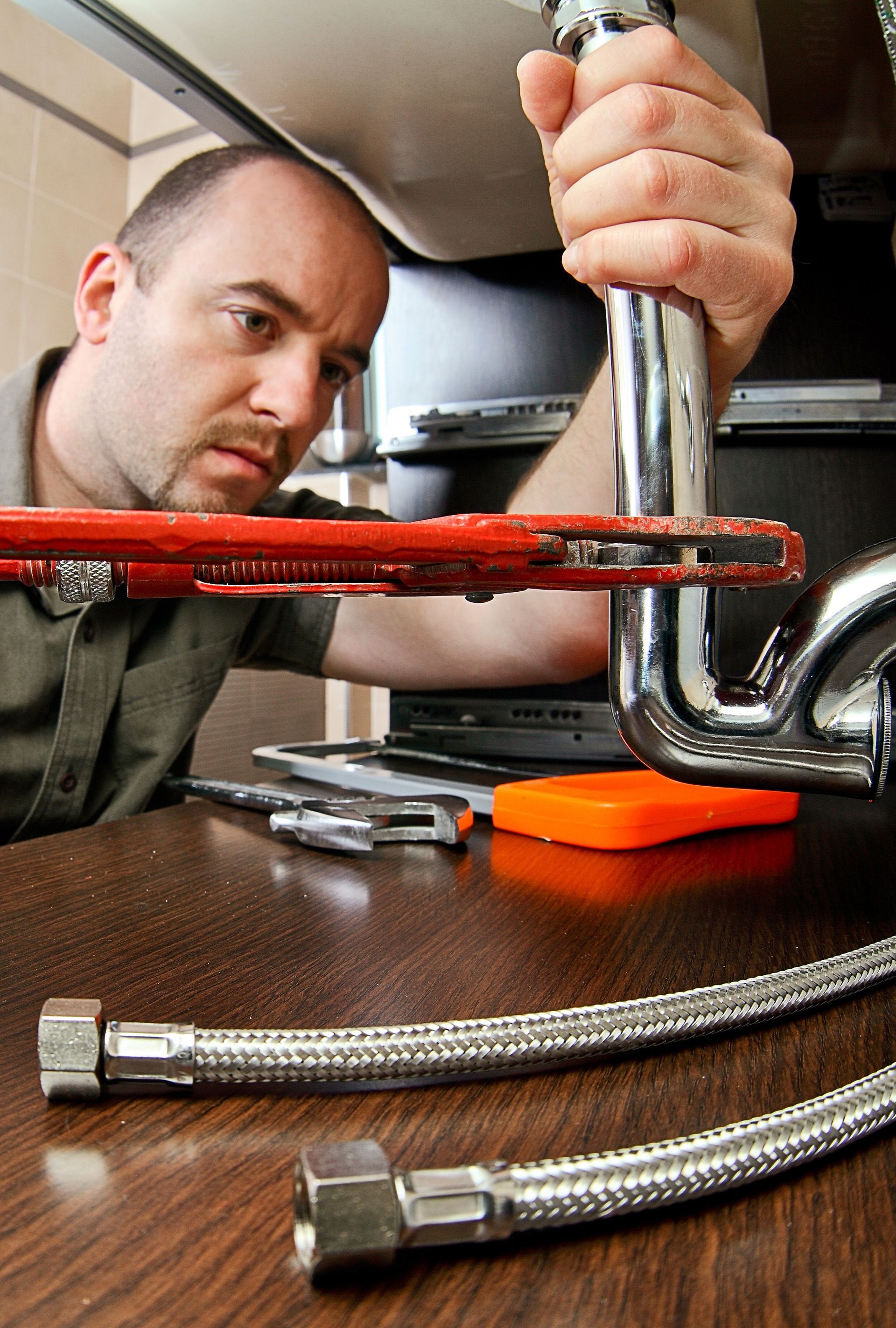 A man is fixing a pipe with a wrench.