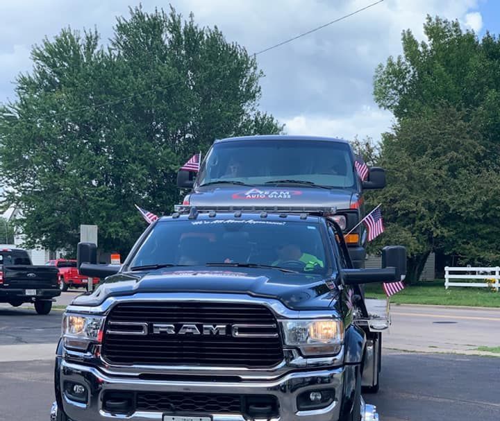 A ram truck is towing a jeep in a parking lot.