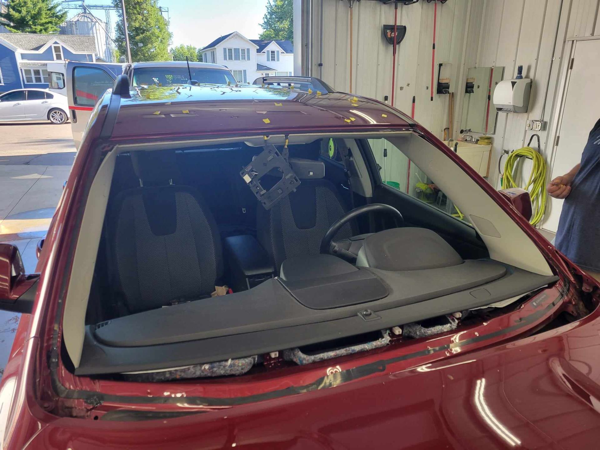 A red car with a broken windshield is parked in a garage.