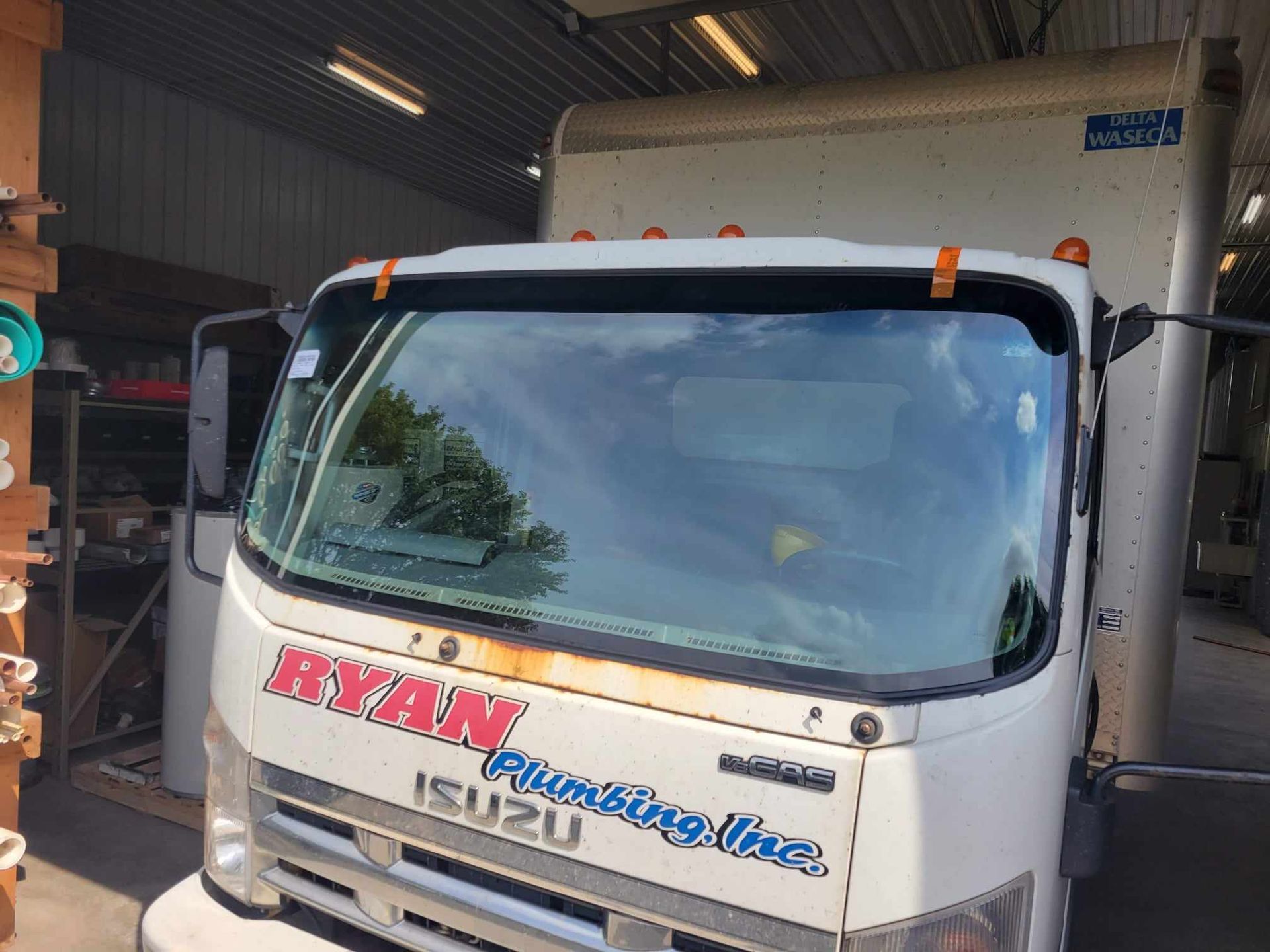 A white ryan plumbing truck is parked in a garage.
