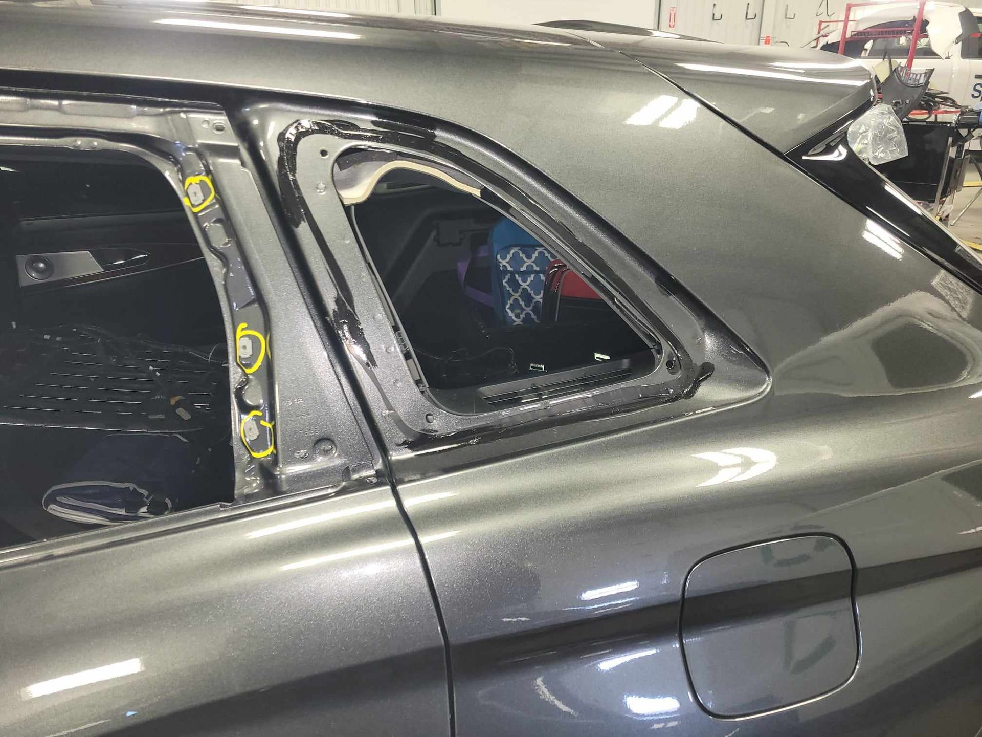 A gray car with a broken window in a garage