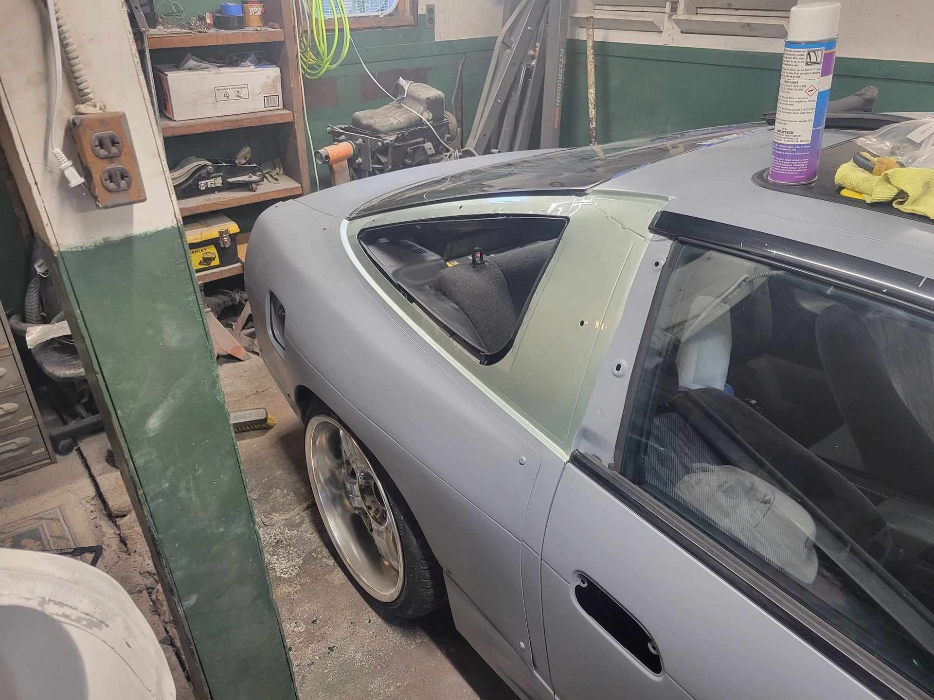 A gray car is parked in a garage with a spray bottle on top of it.