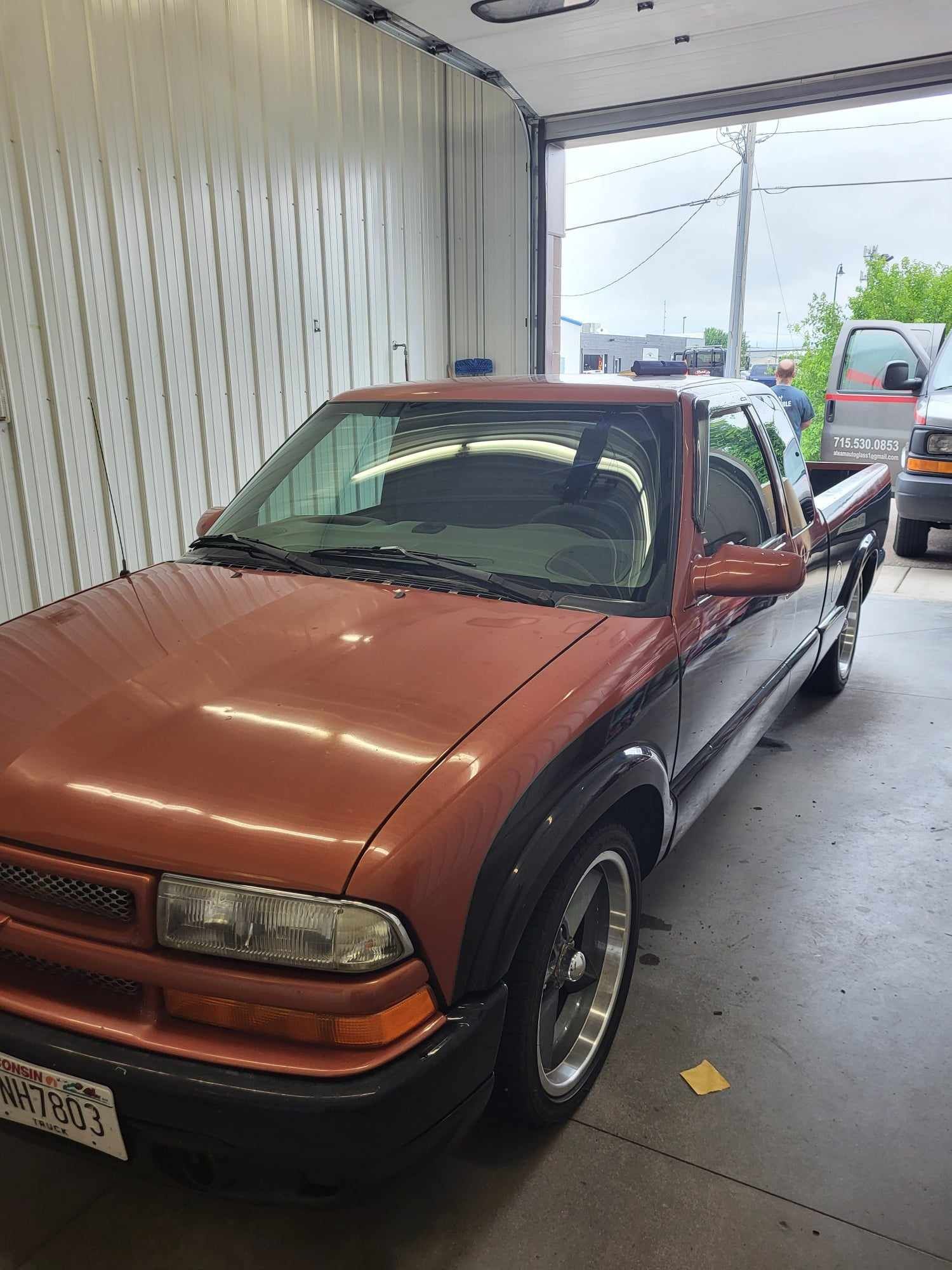 A red truck is parked in a garage next to a white wall.