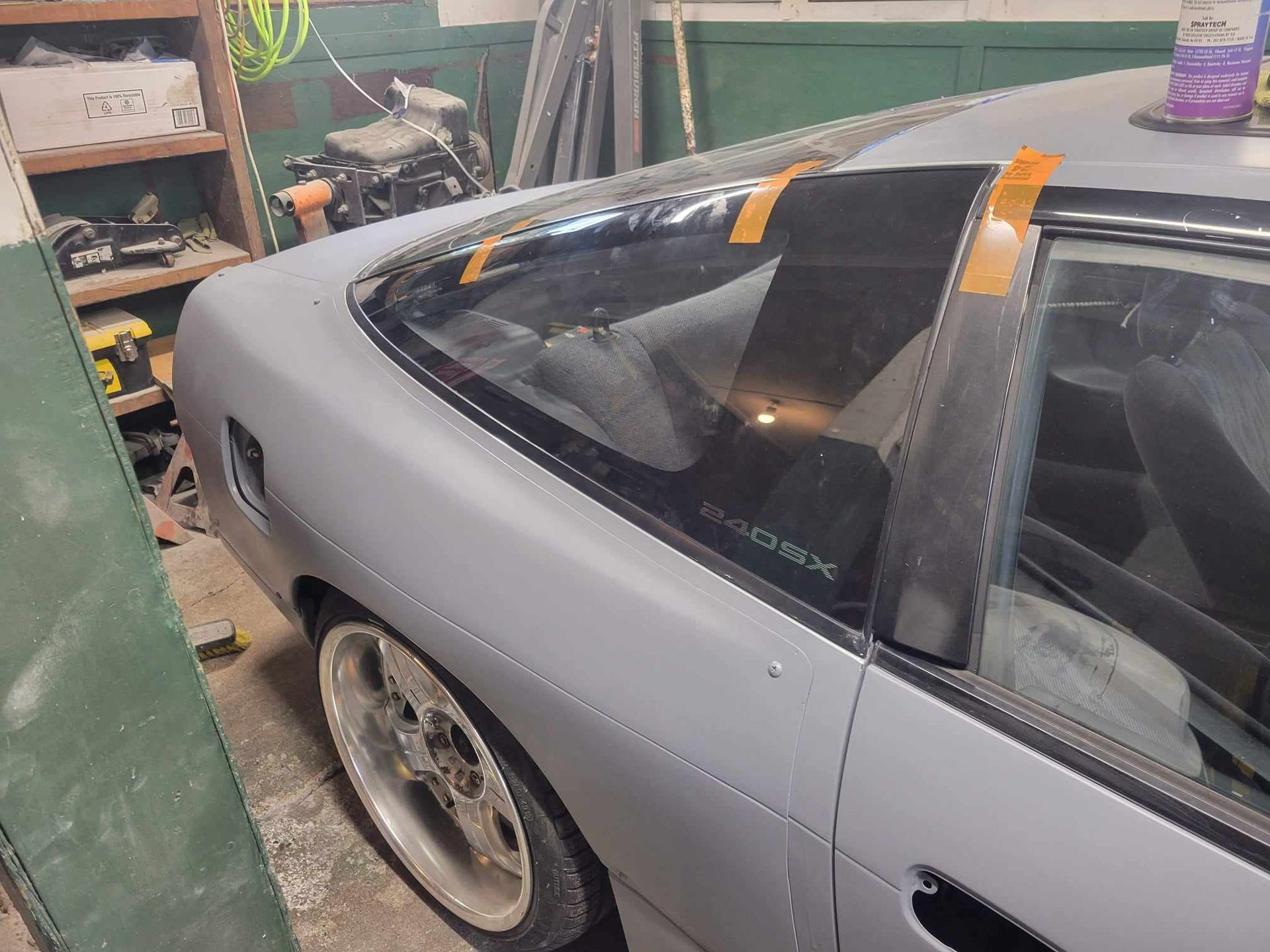 A car is sitting in a garage with tape on the windshield.